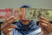 Petugas menunjukkan uang pecahan dolar AS dan rupiah di gerai penukaran mata uang asing(Foto Antara)