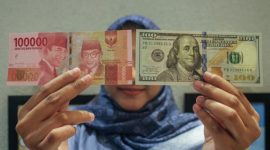 Petugas menunjukkan uang pecahan dolar AS dan rupiah di gerai penukaran mata uang asing(Foto Antara)