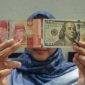 Petugas menunjukkan uang pecahan dolar AS dan rupiah di gerai penukaran mata uang asing(Foto Antara)