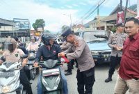 Kabag Ops Polres Kerinci AKP Yudi Stira membagikan bendera merah putih kepada pengendara di Kota Sungai Penuh, Selasa (5/8/2025).