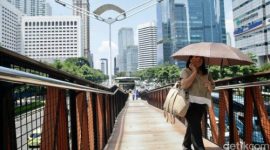 Warga Jakarta melindungi diri dari teriknya matahari saat cuaca panas ekstrem melanda ibu kota, 