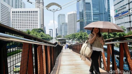 Warga Jakarta melindungi diri dari teriknya matahari saat cuaca panas ekstrem melanda ibu kota, 