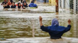 Sejumlah warga melintasi jalan permukiman yang terendam banjir tinggi saat proses evakuasi.