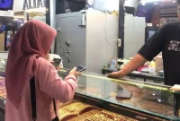 Pedagang menunjukkan logam mulia yang dijual di Toko Emas Amalia, Batang Hari.
