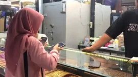 Pedagang menunjukkan logam mulia yang dijual di Toko Emas Amalia, Batang Hari.