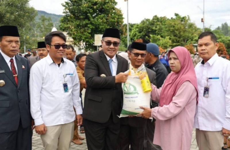 Wali Kota Sungai Penuh Alfin menyerahkan bantuan pangan kepada warga, didampingi Wawako Azhar Hamzah, Kepala Bulog, dan Kepala Dinas Ketahanan Pangan.