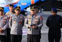 Personel kepolisian memberikan keterangan pers di area bandara sebelum pengiriman bantuan logistik untuk penanganan bencana.
