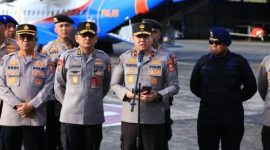 Personel kepolisian memberikan keterangan pers di area bandara sebelum pengiriman bantuan logistik untuk penanganan bencana.