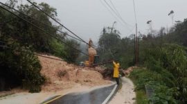 Seorang petugas memeriksa kondisi jalan yang tertutup longsor dan tiang listrik tumbang di tengah hujan deras pada jalur Tapanuli–Sibolga.