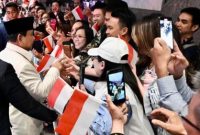 Presiden Prabowo Subianto menerima bunga dari anak-anak Indonesia saat tiba di hotel di Sydney, disaksikan para diaspora dan pejabat pemerintah.