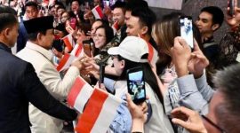Presiden Prabowo Subianto menerima bunga dari anak-anak Indonesia saat tiba di hotel di Sydney, disaksikan para diaspora dan pejabat pemerintah.