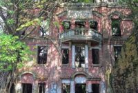 Tampak depan Rumah Hantu Minxiong di Taiwan yang kini dipenuhi lumut dan pohon liar, memberi kesan angker seperti di film horor.