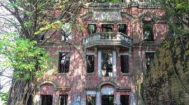 Tampak depan Rumah Hantu Minxiong di Taiwan yang kini dipenuhi lumut dan pohon liar, memberi kesan angker seperti di film horor.