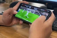 Seorang pemain memainkan game FC Mobile EA Sports melalui ponsel saat pertandingan virtual berlangsung.