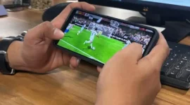 Seorang pemain memainkan game FC Mobile EA Sports melalui ponsel saat pertandingan virtual berlangsung.