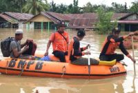Petugas BNPB membawa seorang warga menggunakan perahu karet saat banjir merendam sejumlah rumah di sebuah kawasan permukiman.
