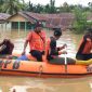 Petugas BNPB membawa seorang warga menggunakan perahu karet saat banjir merendam sejumlah rumah di sebuah kawasan permukiman.