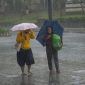 Dua warga berjalan di tengah hujan deras sambil menggunakan payung di salah satu ruas jalan Jakarta.