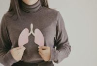 Seorang wanita memegang potongan gambar paru-paru, menggambarkan kesehatan organ pernapasan.