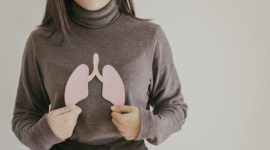 Seorang wanita memegang potongan gambar paru-paru, menggambarkan kesehatan organ pernapasan.