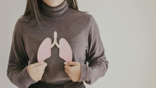 Seorang wanita memegang potongan gambar paru-paru, menggambarkan kesehatan organ pernapasan.