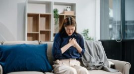 Seorang wanita tampak memegangi dada dan menahan rasa sakit, salah satu tanda yang bisa terkait gangguan jantung.