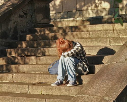 Ilustrasi remaja yang mengalami tekanan emosional akibat perundungan, baik di lingkungan nyata maupun digital.