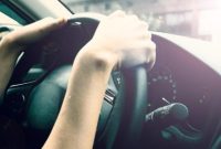 Pengemudi terlihat memegang stir mobil, menggambarkan sensasi perjalanan yang berbeda antara pergi dan pulang