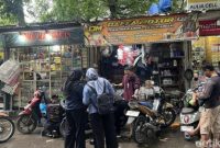 Seorang mekanik memperbaiki motor yang mogok setelah menerjang banjir di kawasan Jakarta Utara, Senin (12/1/2026).