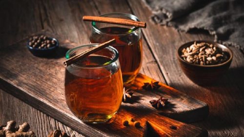 Segelas air rebusan kayu manis hangat yang dikenal memiliki berbagai manfaat kesehatan alami.