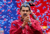 Presiden Venezuela tampil di hadapan pendukungnya saat sebuah acara politik, dengan konfeti berhamburan di latar belakang.