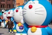 Seorang anak sedang bermain di antara patung boneka Doraemon (Foto: Freepik)
