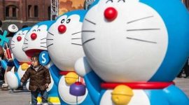 Seorang anak sedang bermain di antara patung boneka Doraemon (Foto: Freepik)