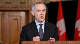Perdana Menteri Kanada, Mark Carney, menyampaikan pernyataan resmi di hadapan media dengan bendera Kanada di belakangnya.