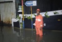 Warga melintasi banjir yang merendam permukiman di Jakarta, Senin (12/1/2026). BPBD mencatat banjir masih menggenangi puluhan RT dan ruas jalan.