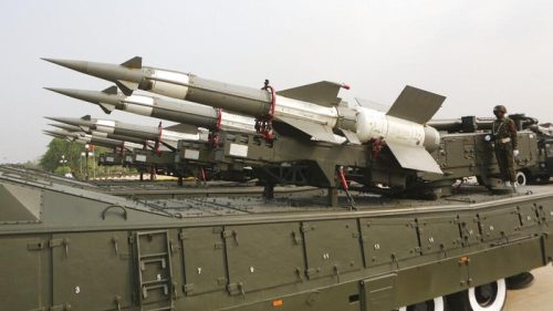Deretan rudal permukaan-ke-udara terlihat siap diluncurkan dari kendaraan militer, sementara seorang tentara mengawasi di sampingny