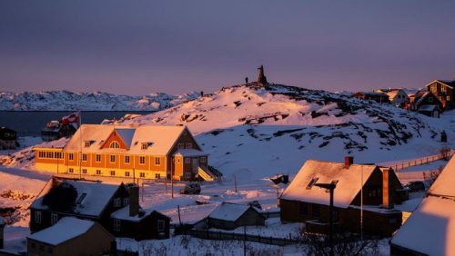 Pemandangan wilayah Greenland yang didominasi lapisan es dan pegunungan, dengan kawasan permukiman di pesisir ibu kota Nuuk.