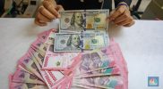 Pecahan rupiah dan dolar AS ditampilkan di gerai penukaran uang di Jakarta.