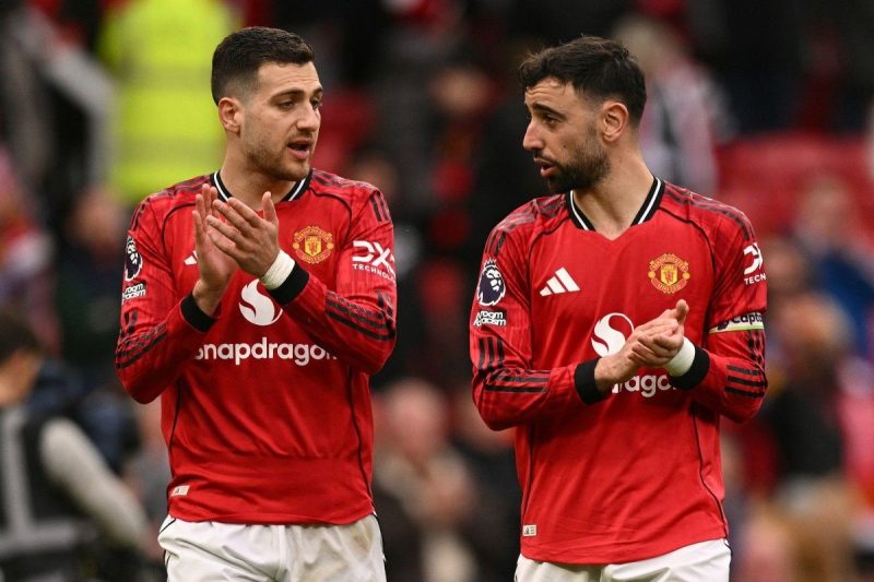 Diogo Dalot dan Bruno Fernandes menyapa suporter usai laga Manchester United vs Aston Villa di Old Trafford, 15 Maret 2026. (AFP/Oli Scarff)