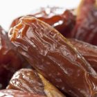 Tampilan kurma Tunisia jenis deglet nour yang memiliki warna cokelat keemasan, permukaan halus, dan daging buah semi-transparan.