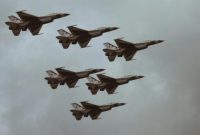 Formasi jet tempur dalam penerbangan di langit berawan.