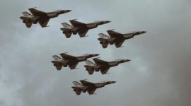 Formasi jet tempur dalam penerbangan di langit berawan.