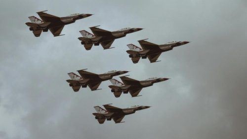 Formasi jet tempur dalam penerbangan di langit berawan.