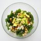 Semangkuk salad sehat berisi bayam segar, potongan alpukat, bawang, tomat, dan kacang chickpea yang kaya protein nabati.