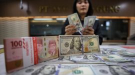 Karyawan menunjukan mata uang dolar AS dan rupiah di salah satu tempat penukaran uang di Jakarta