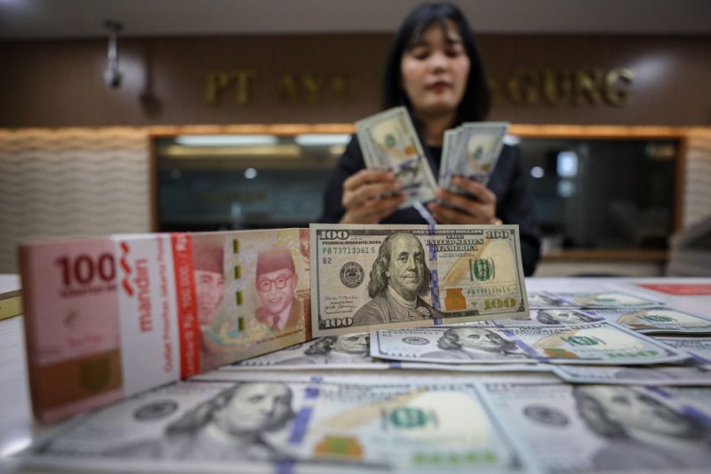 Karyawan menunjukan mata uang dolar AS dan rupiah di salah satu tempat penukaran uang di Jakarta
