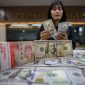 Karyawan menunjukan mata uang dolar AS dan rupiah di salah satu tempat penukaran uang di Jakarta