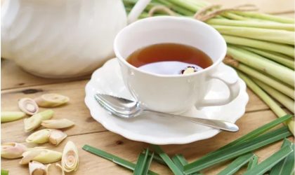 Air serai hangat dalam gelas dengan batang serai segar