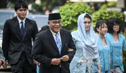 Mohammad Jumhur Hidayat berjalan menuju pelantikan di Istana Negara, Jakarta, bersama keluarga.