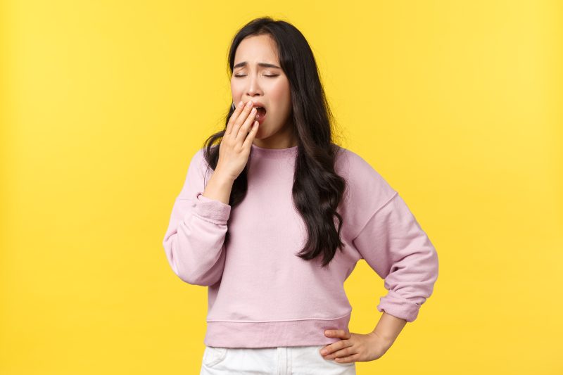 Lifestyle, emotions and advertisement concept. Tired asian female employee wants sleep, feeling exhausted after long nish, yawning, covering opened mouth with hand, wake-up early.